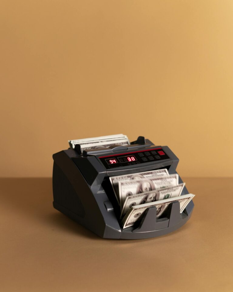 Electronic money counter processing US dollars on a neutral background.